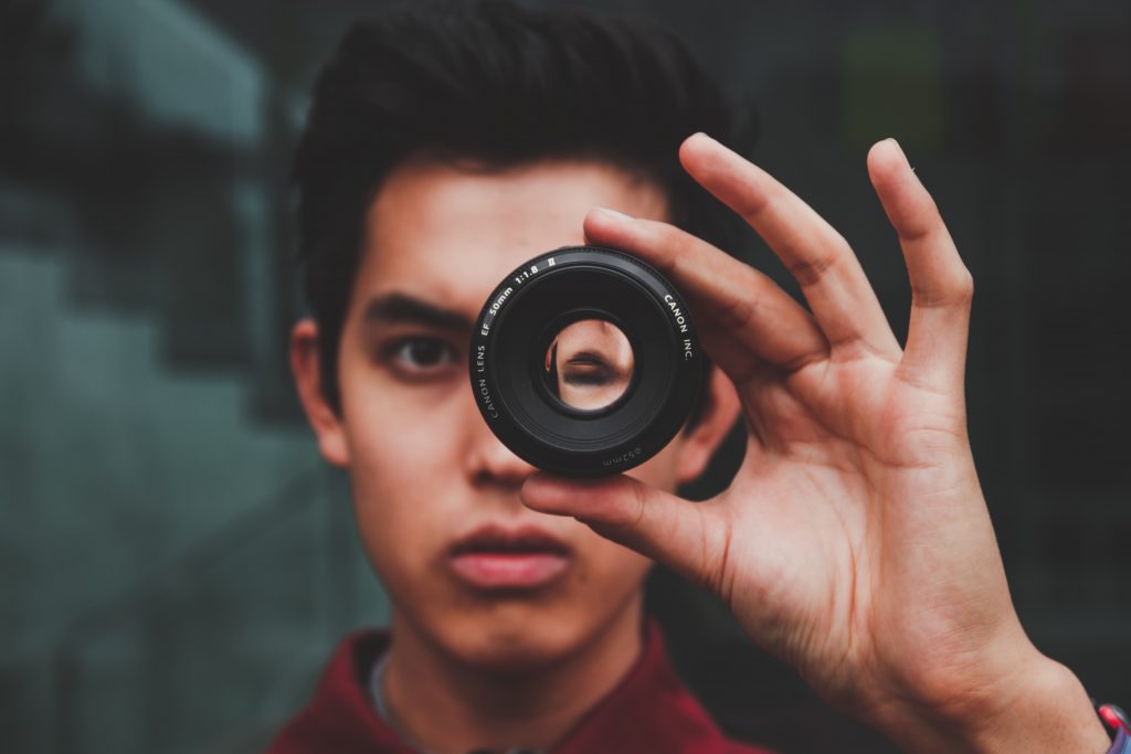 man looking through a camera lens